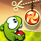 Cute green monster reaching for a hanging red and white candy in a physics puzzle game